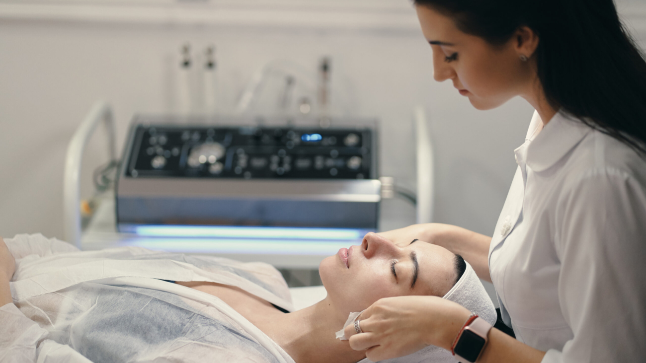 Esthetician performing a HydraFacial on a client in a modern skincare clinic.