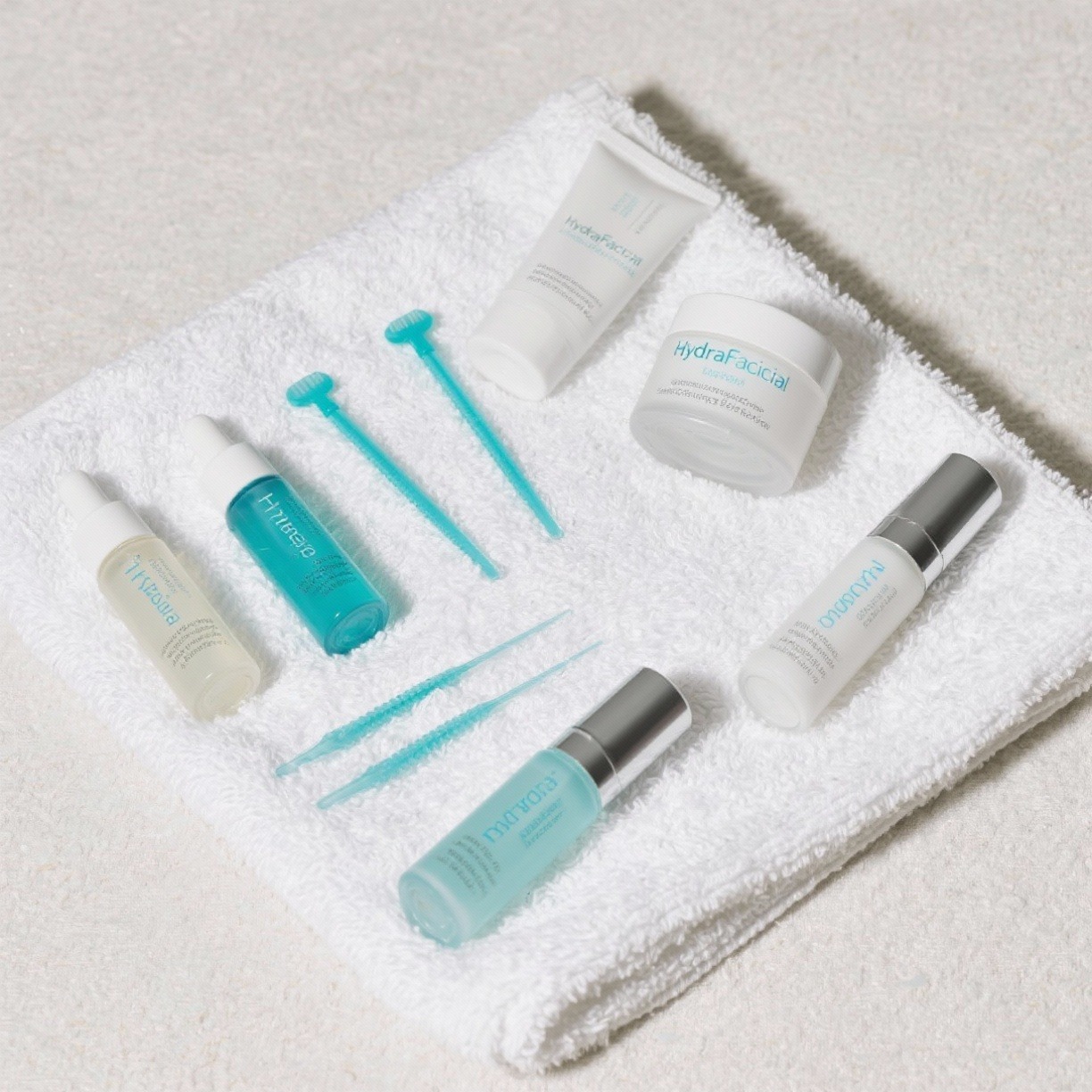 Flat lay of HydraFacial tips, serums, and skincare boosters on a clean spa towel.