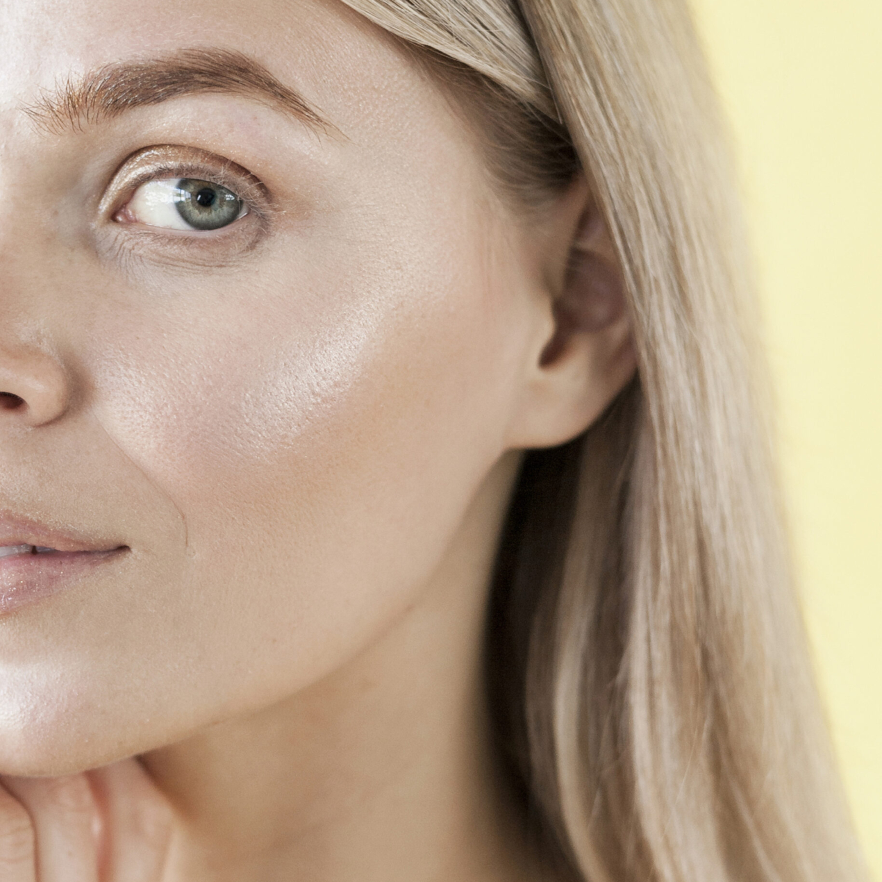 Woman with radiant, dewy skin smiling in natural sunlight.