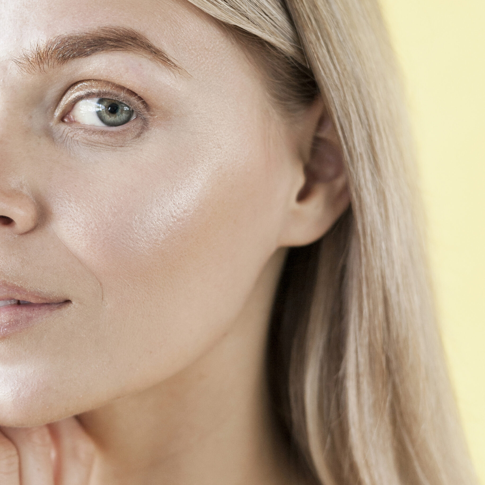 Woman with radiant, dewy skin smiling in natural sunlight.